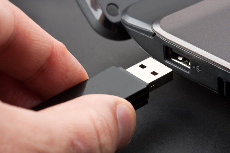 Hand holding a failed flash Drive being that is being ejected from laptop for flash drive data recovery services